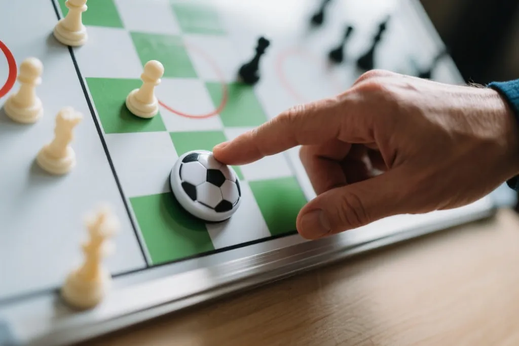 战术板上的磁铁棋子与足球教练的手指，专注而严谨